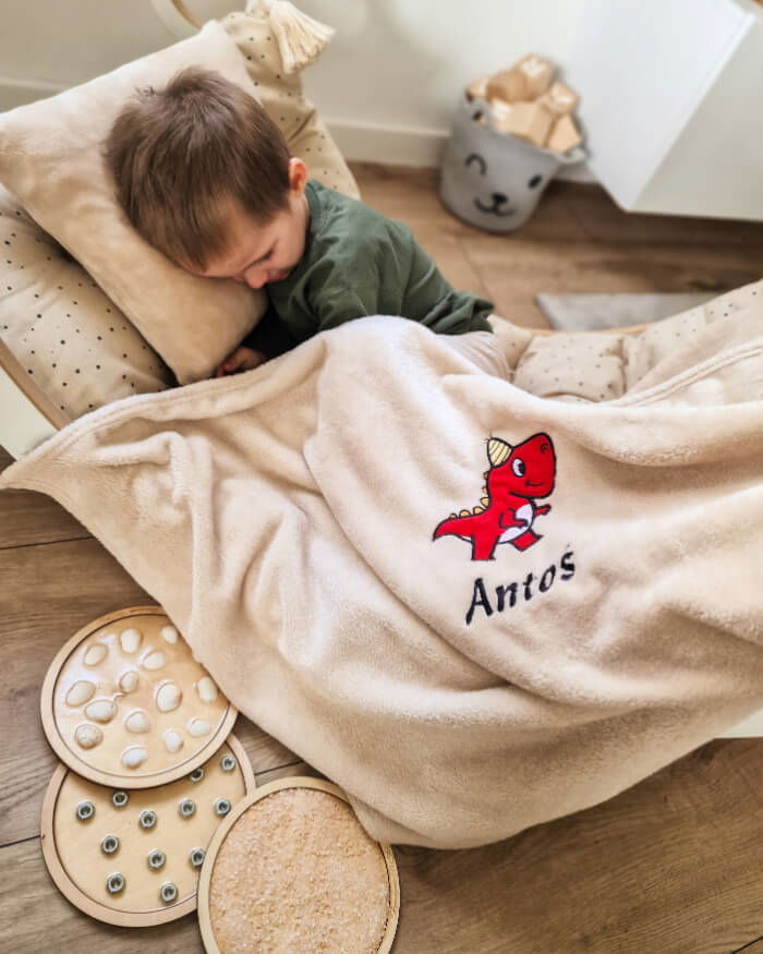 Young boy Antos covered with his personalized blanket