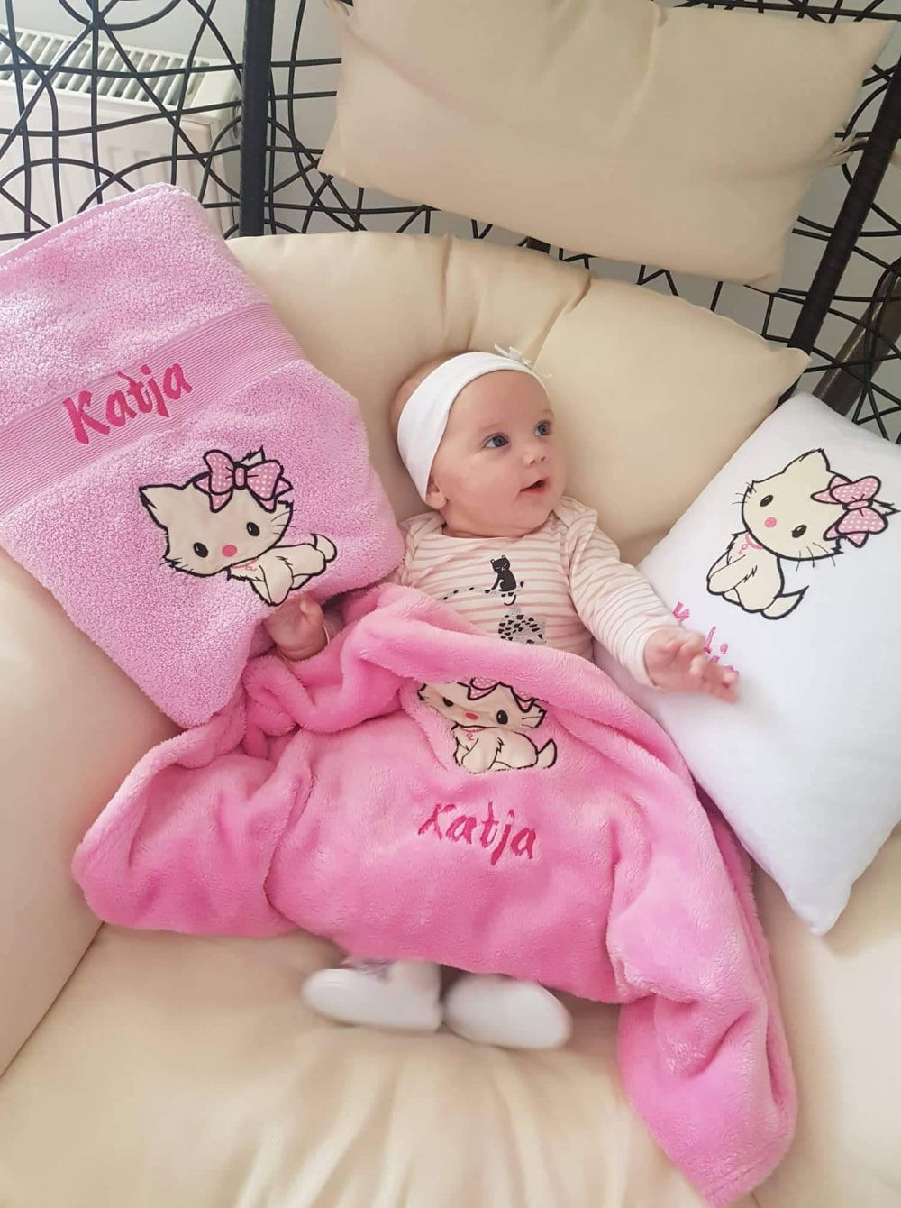 Adorable baby girl is enjoying her personalized set consisting of a pillow, blanket, and towel, all customized with her name.