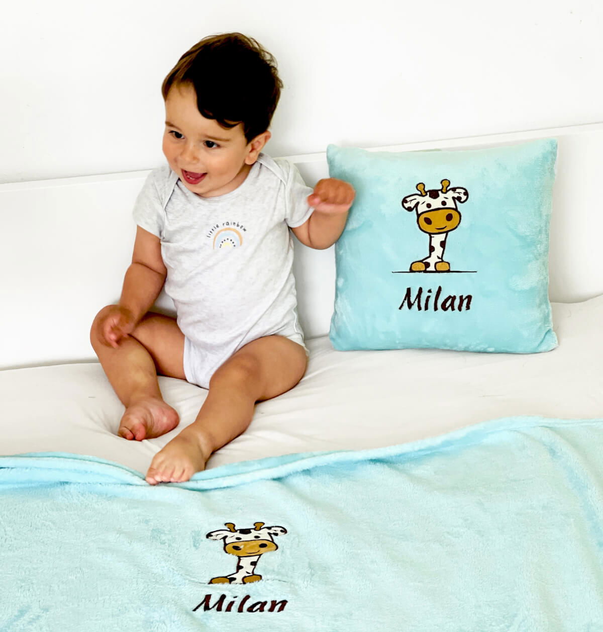 Adorable boy rests peacefully on his bed, snuggled up with a soft and cozy personalized pillow and blanket, customized with his name and a charming design.