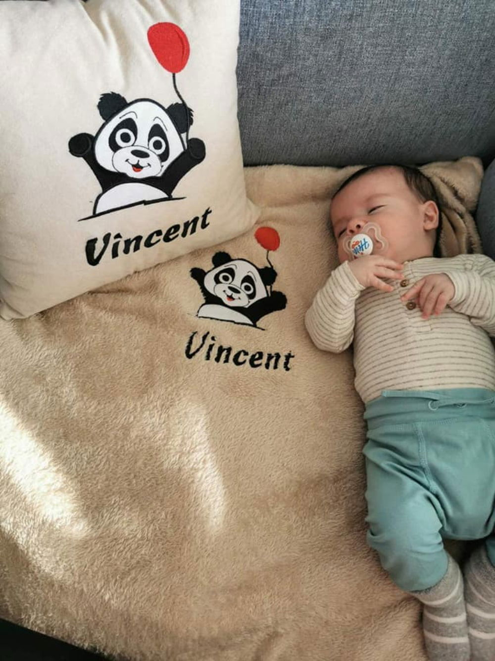 Adorable baby boy rests peacefully on his bed, snuggled up with a soft and cozy personalized pillow and blanket, customized with his name and a charming design.